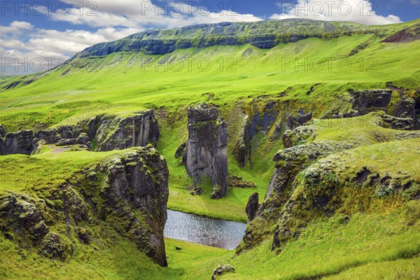 Bizarre shape of cliffs surround the stream with glacial water. The striking canyon in Iceland. The concept of active tourism