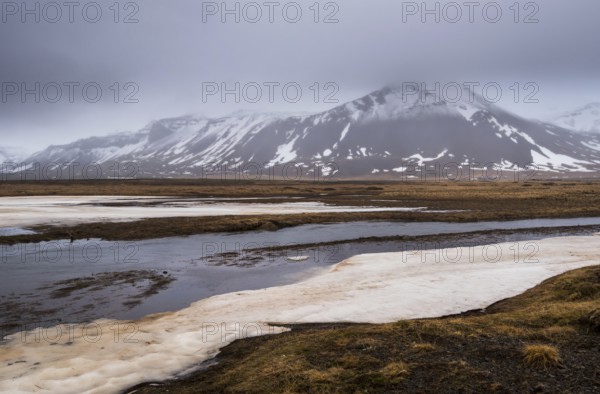 Icelandic landscape with frozen lake, mountains and meadow land covered in snow at snaefellsnes peninsula in Iceland
