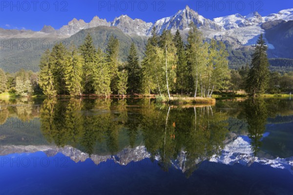 Dreamlike beauty lake and park. In smooth water reflected snow-capped mountains surrounding the mountain resort of Chamonix