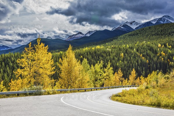 Gorgeous stormy sky in October. Road among autumn forest. Rocky Mountains of Canada