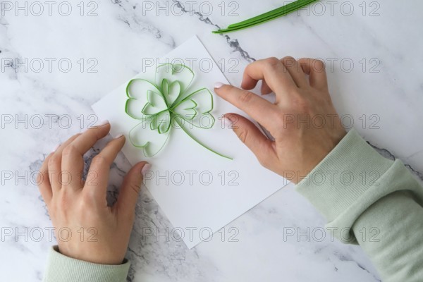 Diy St. Patricks Day greeting card made of Quilling and paper clovers on white background. Gift idea, decor Spring, happy Patrick Day. Step by step. Top view. Process kid children craft. Do it yourself