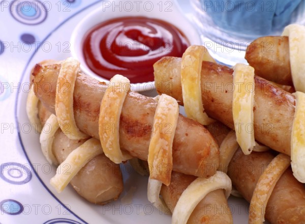 Fresh baked twisted pastry around chicken sausages with ketchup