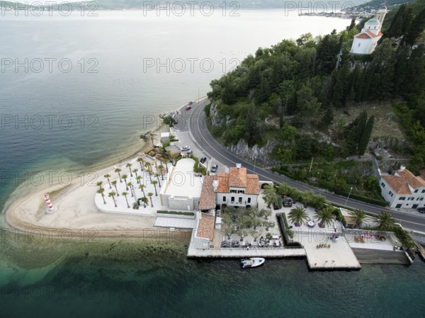 Cozy hotel on a green cape with a beach and a pier. Lepetane, Montenegro. Drone.