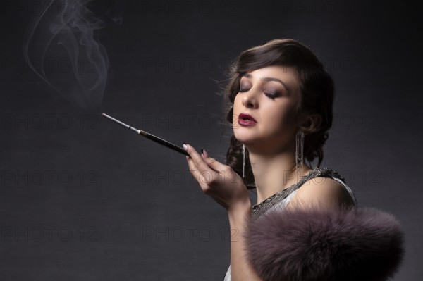 Retro portrait of a woman. A beautiful woman in the style of the 20s and 30s with a cigarette holder smokes