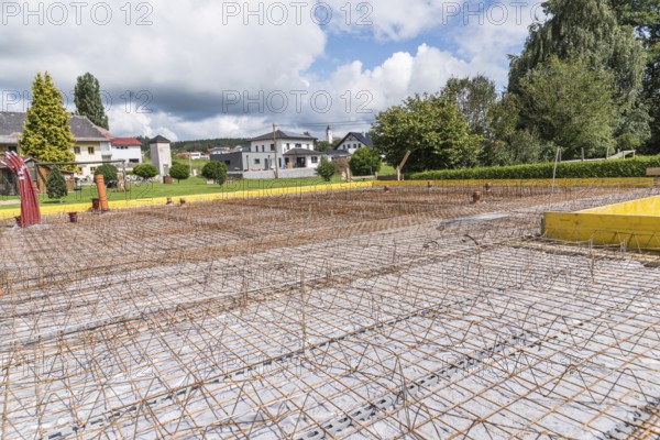 House construction site with steel grid for concrete foundation slab, construction industry