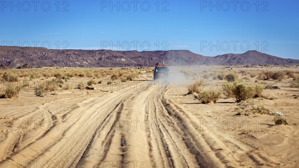 An off-road vehicle drives on a dusty sandy track in an arid desert, With the off-road vehicle through the Sahara in Algeria