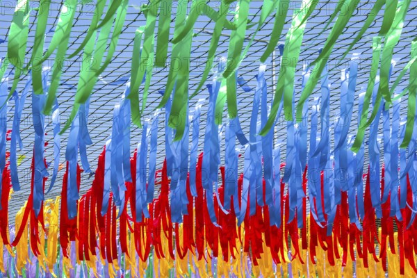Close up shot of decorative multicolor ribbons waving in the wind at city street holiday, festival or carnival. City festival concept. Street decorations