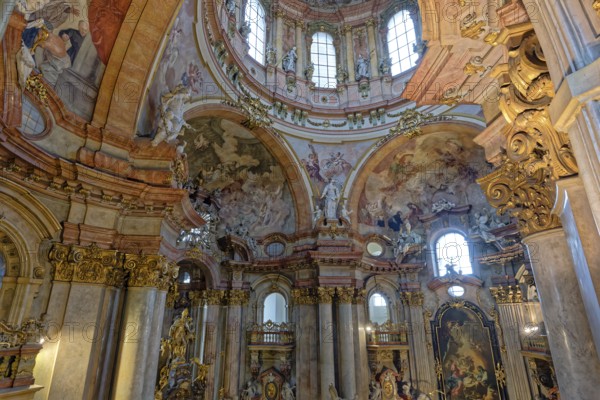 Ornate baroque church interior adorned with frescoes, statues, and warm-colored arches, St. Nicholas Church, Prague, Czech Republic, Europe