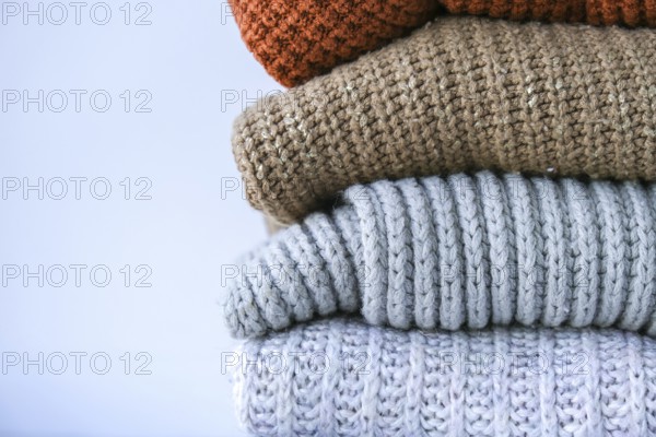 Stack of cozy knitted warm sweater. Sweaters in retro Style. Orange and blue colors. Cozy hygge concept Copy space Autumn winter season