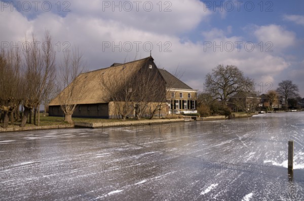 Frozen river the Graafstroom with on the other side a monumental farm in the South Holland village of Bleskensgraaf