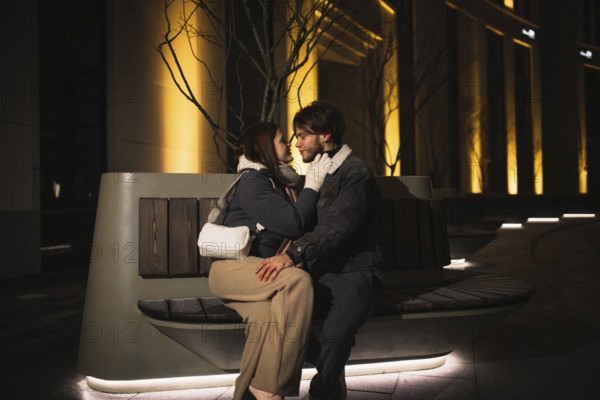 Close couple talking intimately on a bench at night in a city setting