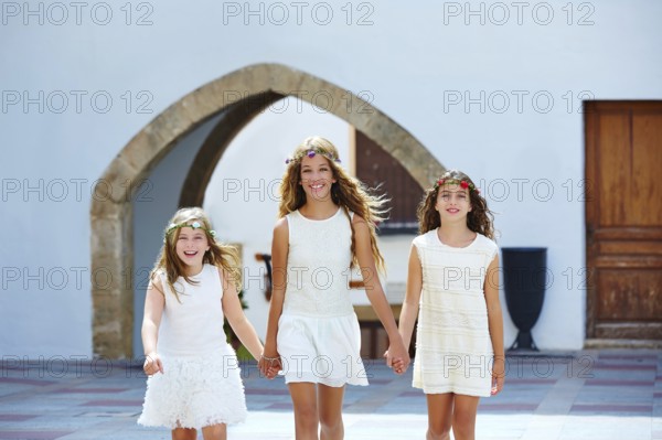 Kid girls walking hand in hand at white Mediterranean village of Spain