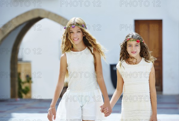 Kid girls walking hand in hand at white Mediterranean village of Spain