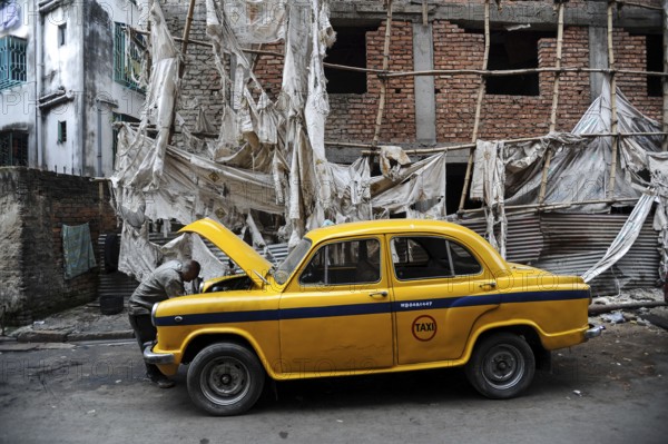 03.12.2011, Kolkata (Calcutta), West Bengal, India, Asia, A taxi driver looks under the bonnet of his yellow Hindustan Ambassador taxi. The Ambassador was the first car manufactured in India and was produced from 1958 to 2014, Asia