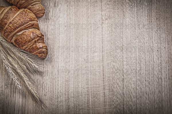Ripe wheat rye ears fresh-baked croissants on wooden board