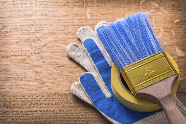 Protective gloves paint brush and duct tape on wooden board construction concept