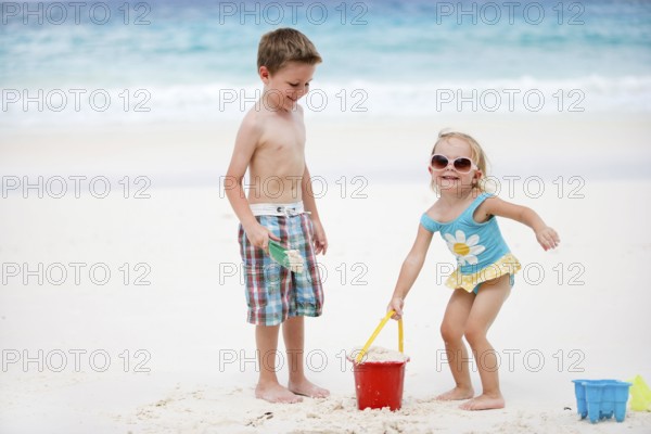 Boy and girl playing in the sand on the beach, La Digue, Indian Ocean, Seychelles, Africa