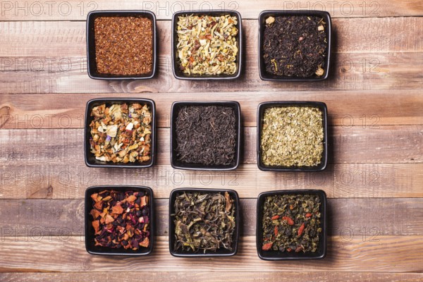 Various tea in a black ceramic bowls on a wooden table