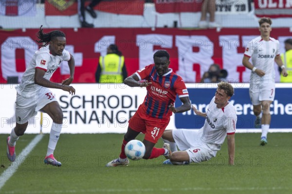 Football match, Sirlod CONTEH 1. FC Heidenheim centre can only be stopped with a foul by Patrick Osterhage SC Freiburg, Jordy MAKENGO SC Freiburg left Football stadium Voith-Arena, Heidenheim