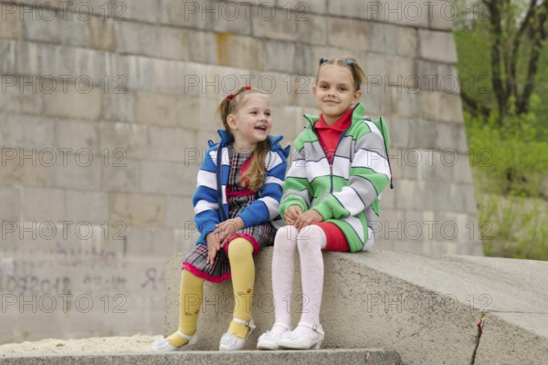 Two girls of four and six years of walking on the embankment of the river