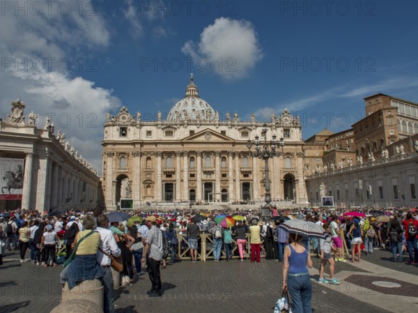 St Peter's Basilica with a large crowd in the square in front of it under a clear blue sky, rome, italy
