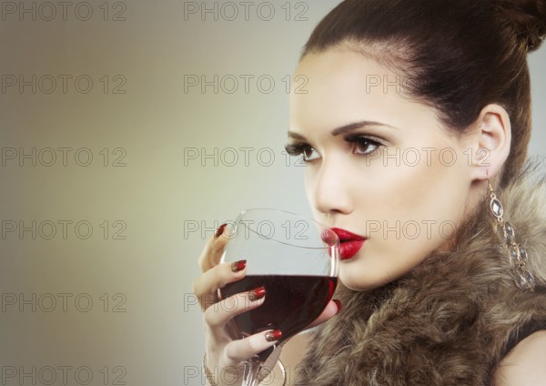 Beautiful woman with dark makeup and red lipstick posing on light grey background. Drinking glass of red wine, Toronto, Canada, North America