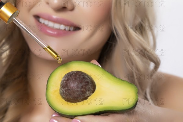 A woman skillfully uses avocado in her skincare routine with a dropper, highlighting beauty and health trends