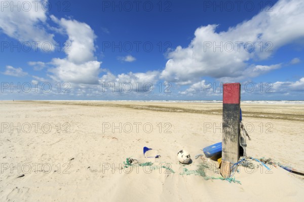 Wooden pole with rubbish at the beach of Dutch wadden island Terschelling