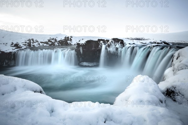 A majestic waterfall surrounded by snow and ice in a wintry landscape, Iceland, Godafoss, Europe