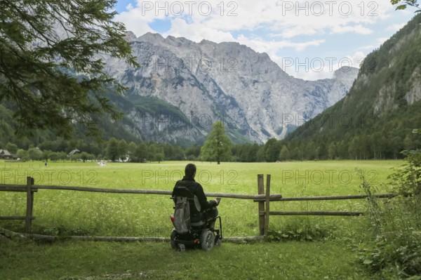 Happy man on wheelchair in nature. Exploring forest wilderness on an accessible dirt path