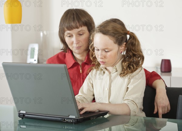 Mother and teenager girl with laptop computer together at home, Belgium, Europe