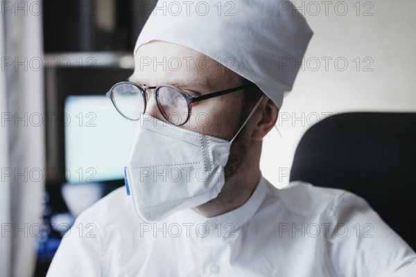 Doctor wearing a mask and glasses in a medical office with an analytical gaze