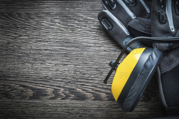 Safety gloves earmuffs on wooden board