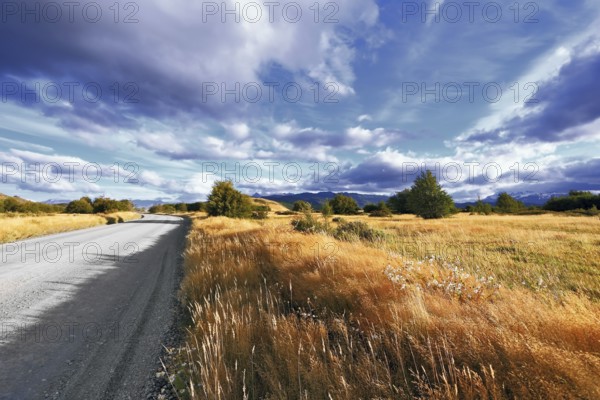 The beginning of autumn in the southern Patagonia. Amazingly beautiful sunset illuminates the distant mountains and the dirt road with bright light