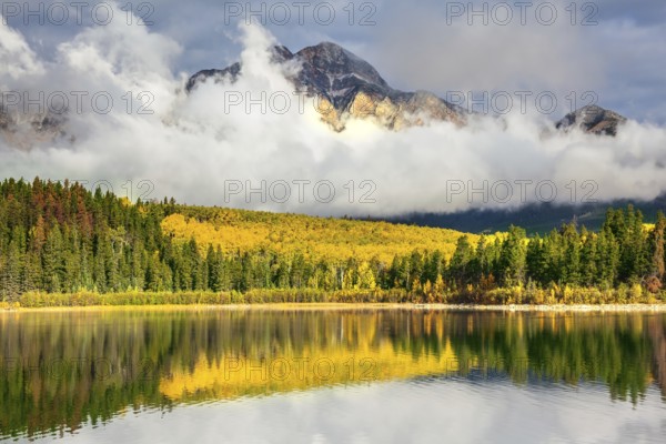 Jasper National Park in the Rocky Mountains of Canada. Patricia Lake. Yellow and orange autumn grass and trees are reflected in cold water