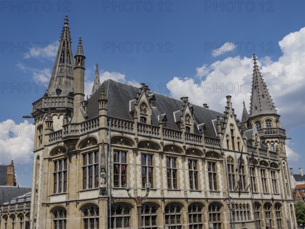 Majestic building with pewter towers and detailed decorations on a clear blue sky, Ghent, Belgium, Europe