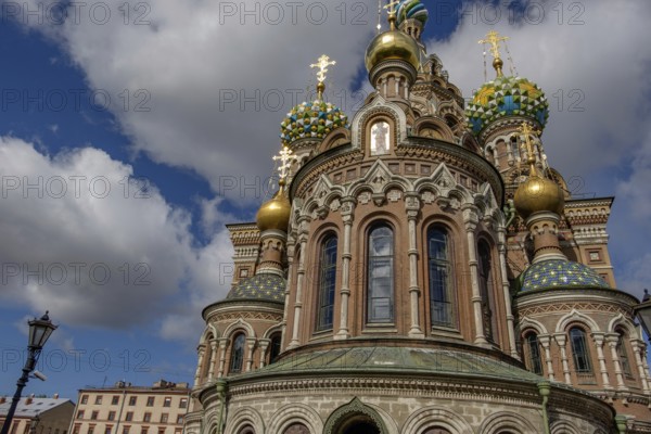 Russian church with magnificent onion domes and richly decorated façades in the sunlight against a white-blue sky