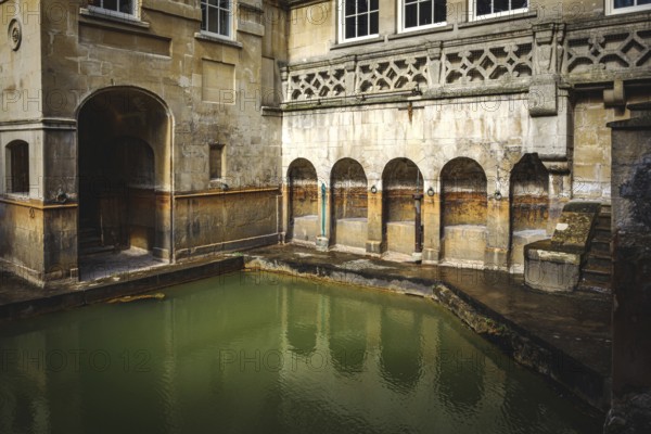 Water and buildings in an old roman bath in the city of Bath in the united kingdom england