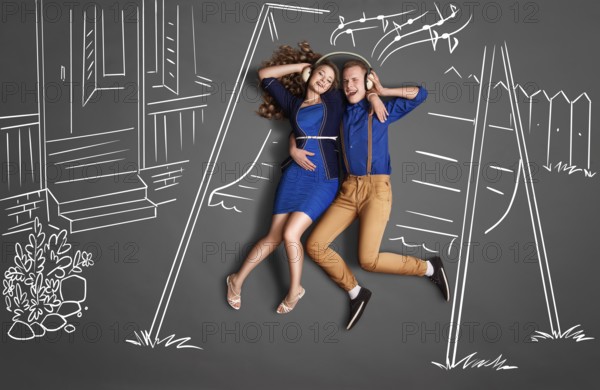 Happy valentines love story concept of a romantic couple sitting on the canopy swing sharing headphones and listening to the music against chalk drawings backyard background