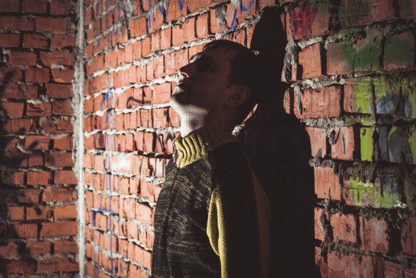 Man leaning on a brick wall in abandoned unfinished house