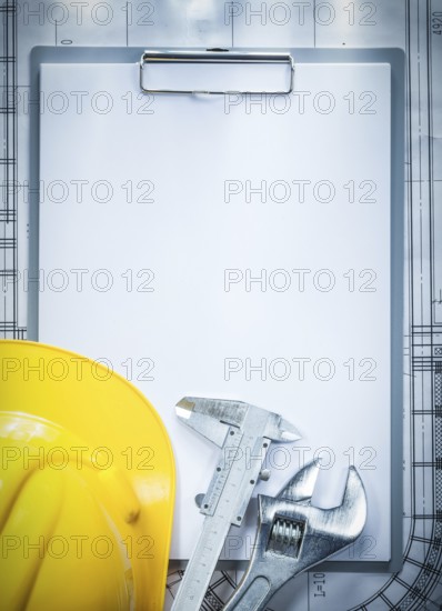 Clipboard building helmet adjustable spanner vernier caliper on blueprint construction concept