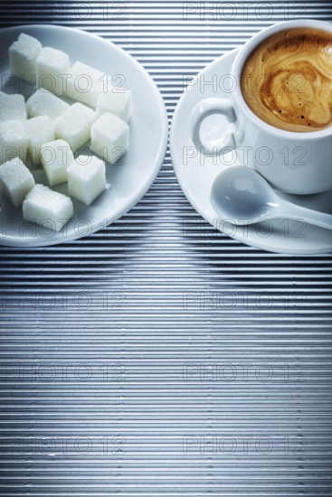 Cup of cappuccino coffee saucer teaspoon sugar cubes on striped background