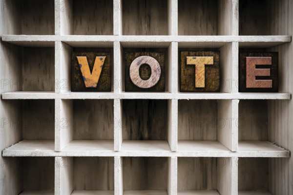 The word VOTE written in vintage ink stained wooden letterpress type in a partitioned printer's drawer