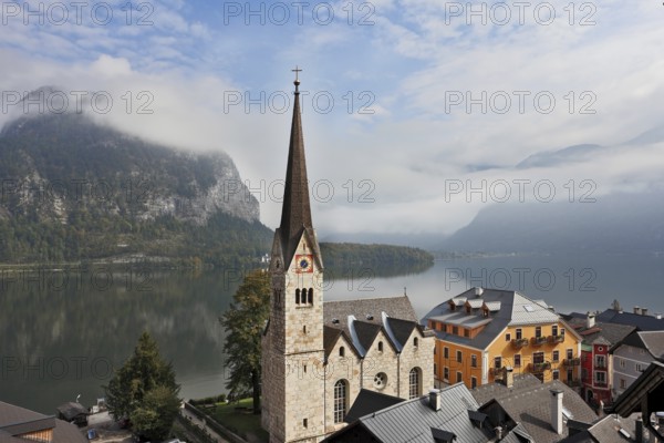 The most picturesque small town in Austria - Hallstatt. Slender belfry and Lutheran church on the shore of Lake Hallstatt. On the opposite shore of the lake - the beautiful mountains overgrown with forests