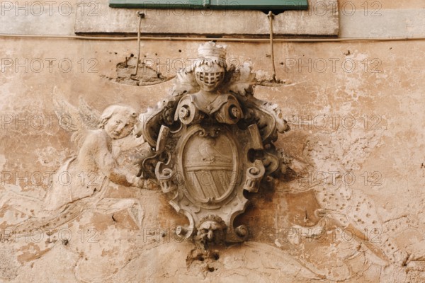 A bas-relief on the facade of a building in the old town of Kotor in Montenegro. Knight's shield and armor, dove and angels.