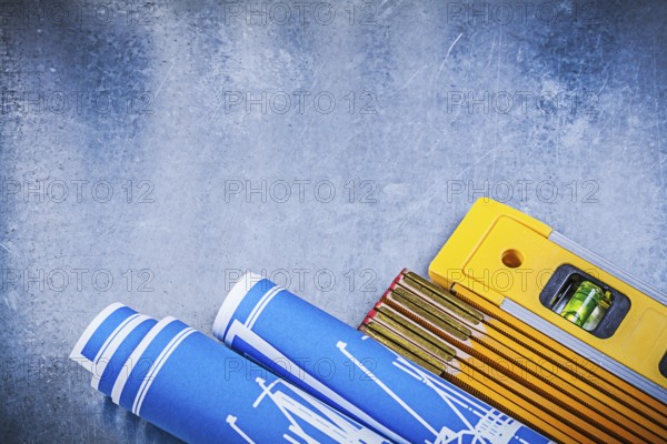 Wooden meter blue rolled construction drawings level on metallic background