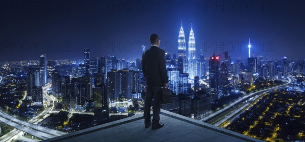 Businessman stand at rooftop looking great cityscape view and thinking business plan of the future . Night scene