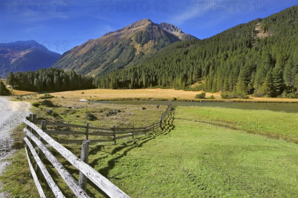 Rural idyll. Headwaters National Park Krimml waterfalls. Farm fields separated from the dirt road the low fence made ??of logs
