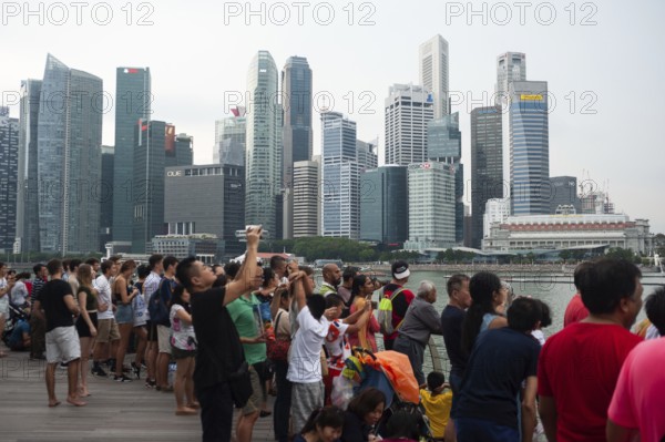 04.08.2018, Singapore, Republic of Singapore, Asia, Visitors watch a flight manoeuvre by the local air force over Marina Bay against the imposing backdrop of the business district in preparation for the annual National Day celebrations, Asia