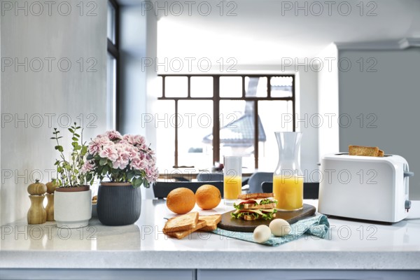 White electric bread toaster with orange juice with sandwich on kitchen table. Breakfast in the cozy kitchen. Useful and tasty food